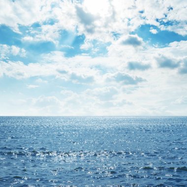 Üzerinde dalgalar ve bulutlar olan mavi deniz.