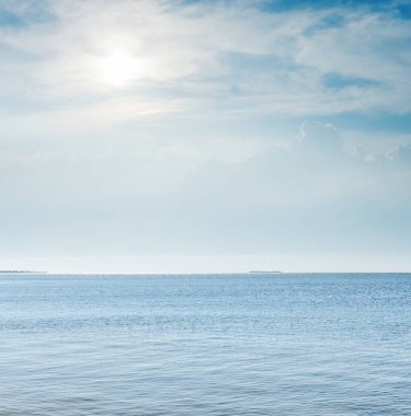 Mavi denizin üzerindeki bulutlarda güneş