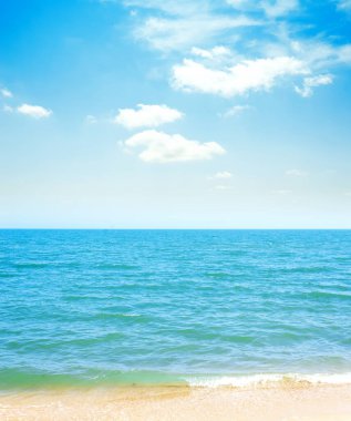 Mavi gökyüzü bulutlu ve deniz sarı kumlu