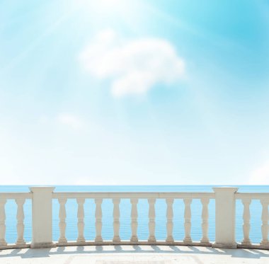 Deniz kenarında teras manzarası ve bulutların üzerinde güneş olan mavi gökyüzü. yumuşak odak