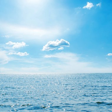 Mavi gökyüzü, bulutlar ve deniz üzerinde güneş.