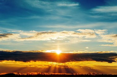 Güneş gün batımında kara bulutların üzerinde