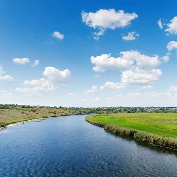 青い空の白い雲の下の緑の風景の中の大きな川 — ストック写真