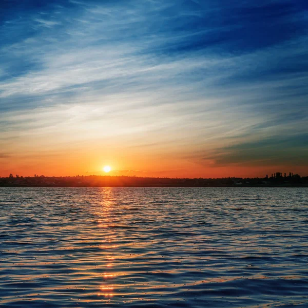 在深蓝色的天空中 天空乌云密布 湖面升起橙色的日出 — 图库照片
