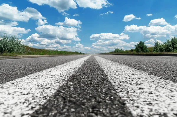 asphalt road closeup to horizon and clouds in blue sky