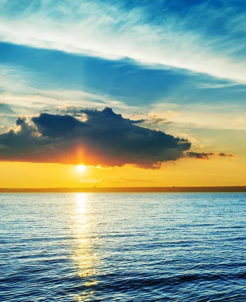 青い川に沈む夕日の暗い劇的な雲 — ストック写真