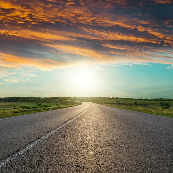 Gün batımında kırmızı bulutlarda ufka giden asfalt yol