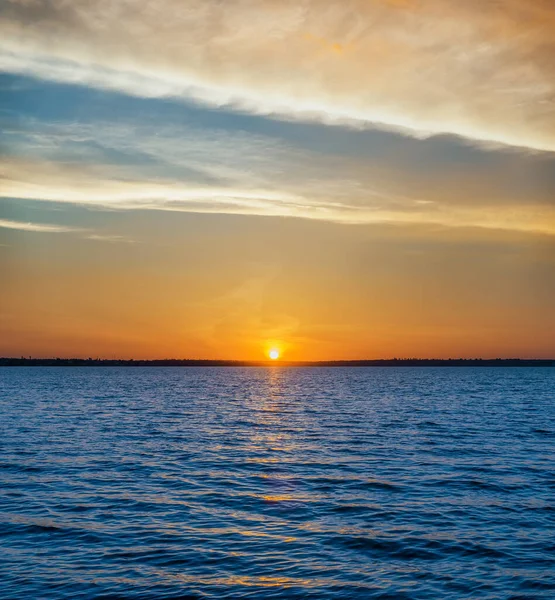 川の青暗い水と雲のオレンジの夕日 — ストック写真