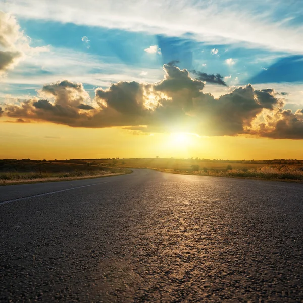 アスファルト道路上の日没で劇的な雲と低太陽 — ストック写真
