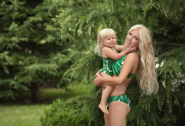 夏の休暇の家族は ブロンドの女の子の親の肖像画を見てください 公園で楽しいファッション緑水着の身に着けている彼女の娘を保持している美しい母親 — ストック写真