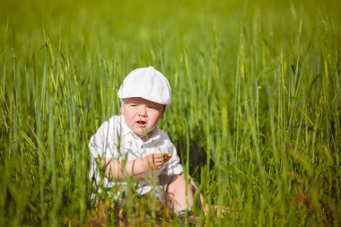 Beyaz şapkalı komik küçük çocuk sakin yaz Park yeşil çim.