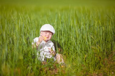 Beyaz şapkalı komik küçük çocuk sakin yaz Park yeşil çim.