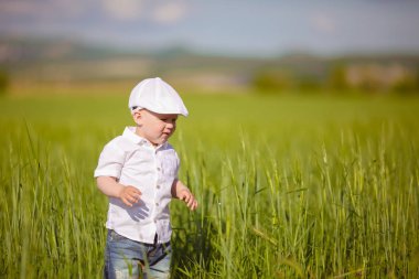 Beyaz şapkalı komik küçük çocuk sakin yaz Park yeşil çim.