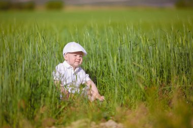 Beyaz şapkalı komik küçük çocuk sakin yaz Park yeşil çim.