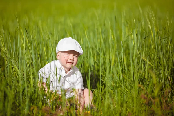 Beyaz şapkalı komik küçük çocuk sakin yaz Park yeşil çim.