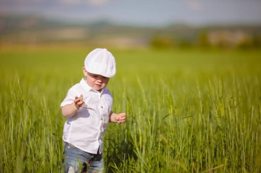 Beyaz şapkalı komik küçük çocuk sakin yaz Park yeşil çim.