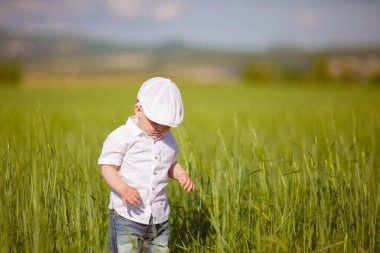Beyaz şapkalı komik küçük çocuk sakin yaz Park yeşil çim.
