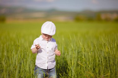 Beyaz şapkalı komik küçük çocuk sakin yaz Park yeşil çim.