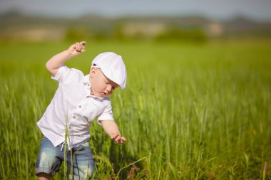 Beyaz şapkalı komik küçük çocuk sakin yaz Park yeşil çim.