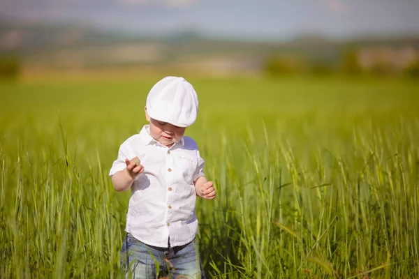 Beyaz şapkalı komik küçük çocuk sakin yaz Park yeşil çim.