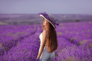 Güzel sağlıklı uzun saçlı. Lavanta alanın üzerine arkadan görünüşü şapkalı genç Genç kız. Günbatımı zevk parlak saç modeli ile mutlu kaygısız kadın. Açık havada dikey. Provence, Fransa.