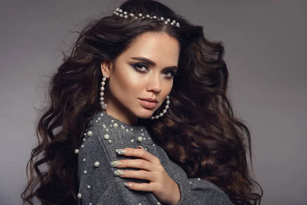 Güzel esmer portre. Güzellik makyaj. İnci takı seti. Kıvırcık uzun saç stili. Manikürlü tırnaklar. Stüdyo gri arka plan üzerinde izole mat ruj ile şehvetli kız modeli.
