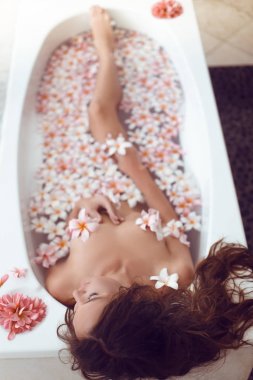 Güzel kadın Plumeria tropikal çiçekler ile banyo zevk. Hge