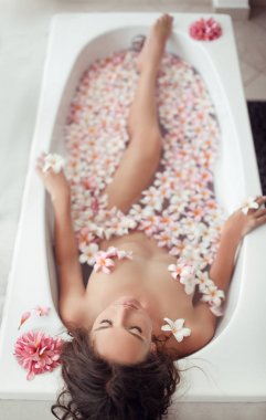 Güzel kadın Plumeria tropikal çiçekler ile banyo zevk. Hge