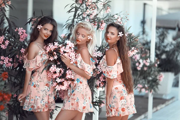 Three beautiful young women in a pretty dress with flowers posin — Stock Photo, Image