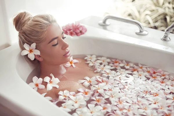 Spa Relájate. Rubia disfrutando de baño con plumeria flores tropicales . —  Fotos de Stock