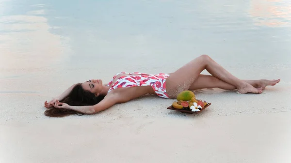 Bekymmerslös brunett kvinna liggande på vit sand njuter av livet på tro — Stockfoto