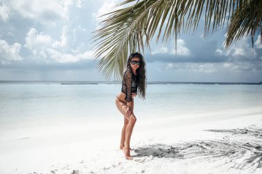 Bikini Modeli palmiye tarafından beyaz kum üzerinde poz. Tropikal esmer 