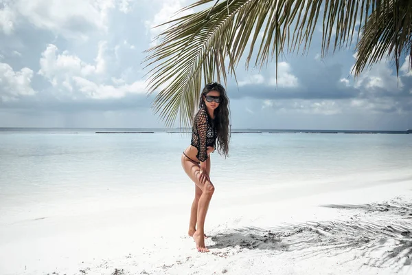 Bikini Modeli palmiye tarafından beyaz kum üzerinde poz. Tropikal esmer 