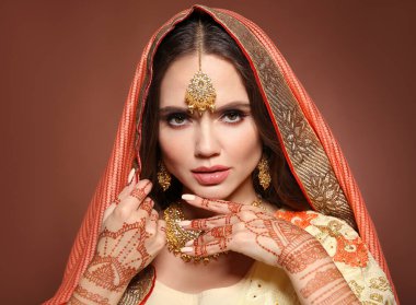 Mehndi. Sari giymiş güzel Hintli kız portresi. Kundan altın mücevher setiyle genç Hindu kadın model. Geleneksel Hint kostümü lehenga choli. Bir kadının ellerinde kına var..