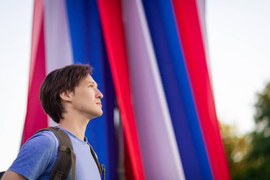 A young man looks to the future against the background of the Russian flag patriot. Russian flag independence day constitution. Russian Federation. 12 June. August 22. November 4th. Citizen. Tricolor  clipart