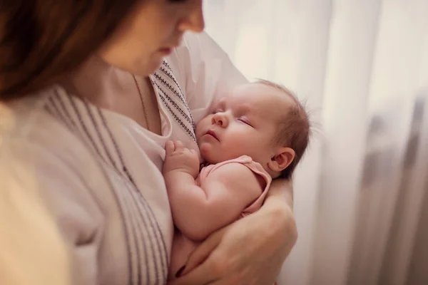 Anne çocuğu sallıyor. Annesinin kollarında uyuyan bir bebeğin portresi. Şefkatli sevgi. Annelik. Ninni söylüyor. Bebek sağlıklı uyku. Genç anne. Küçük tatlı bebek.. 