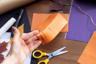 Adım adım talimat. Üçüncü adım: Çocukların el işi kağıt makasları Cadılar Bayramı için balkabağı çelenkleri yapıştırıyor. El yapımı eğlence geliştirme. Çocuk eğitimi yaratıcılık için bir fikirdir. Basit dekor