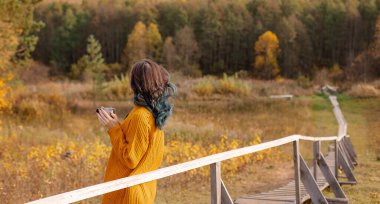 Ilık sonbahar seyahati. Örgü kazaklı bir kız sonbahar manzarasından zevk alır. Rahatlama. Yalnızlık özgürlük sessizliği. Samimi rüyalar. Metin kopyalama alanı için afiş yeri. Yürüyüş turizmi