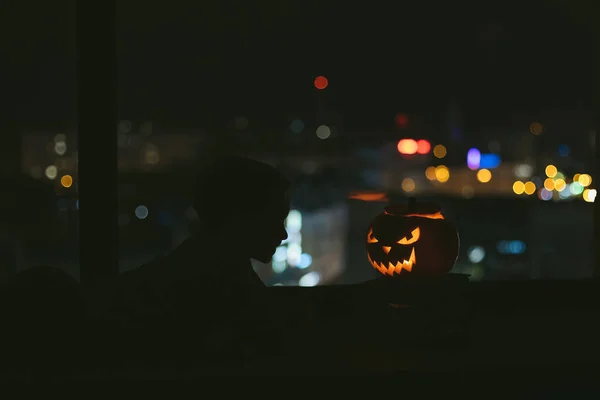 Trick or treat. House party mysterious night, jack o lantern Holiday with children at home leisure entertainment. A child at the window of big city. Scary fun funny.  alone loneliness social distance