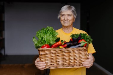 Büyükannem çeşitli sebzelerle dolu bir sepet tutuyor. Yaşlı bir bahçıvan kadın hasatı gösteriyor. Yaşlı bir kadın bir çiftlikten bir paket aldı. Yemek paylaşımı gönüllüsü
