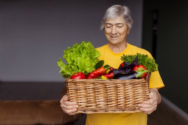 Büyükannem çeşitli sebzelerle dolu bir sepet tutuyor. Yaşlı bir bahçıvan kadın hasatı gösteriyor. Yaşlı bir kadın bir çiftlikten bir paket aldı. Yemek paylaşımı gönüllüsü