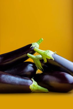 Sarı arka planda mor patlıcan düz yerde yatıyordu. Metin için renkli kopyalama alanı. Pek çok patlıcan sebze vitamini lezzetli olgun sebze eko biyolojisi. Minimalizm deseni yakın plan. çiğ yiyecek.