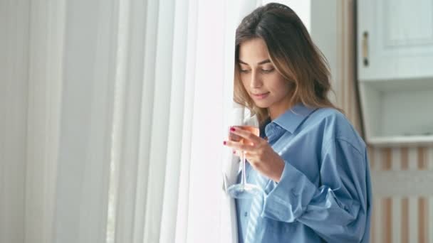 Mujer joven con copa de vino cerca de la ventana — Vídeo de stock