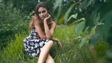 Genç bir kadın çimenlerde oturuyor.