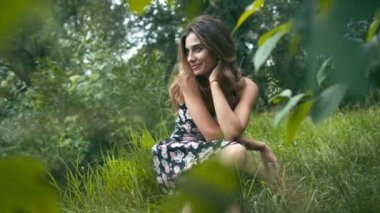 Genç bir kadın çimenlerde oturuyor.