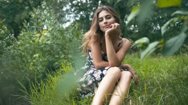 Fiatal nő ül a fűben — Stock videók