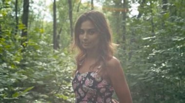 Neşeli genç kadın ormanda yürüyüş road, ağır çekim, sığ derinlik-in tarla. Güneş objektif kamaşma