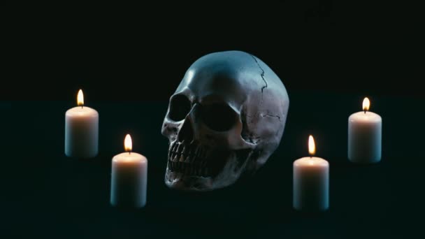 Череп между свечами, тема Хэллоуина — стоковое видео