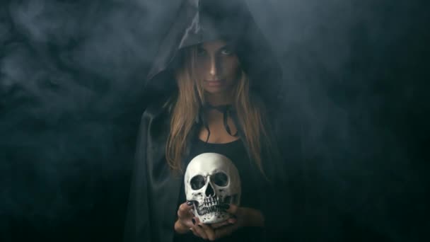 Женщина в черном плаще держит череп — стоковое видео
