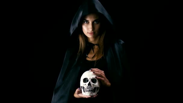 Vrouw in zwarte mantel holding schedel — Stockvideo